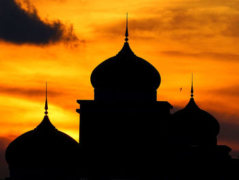 Silhouette mosque against cloudy sky during sunset