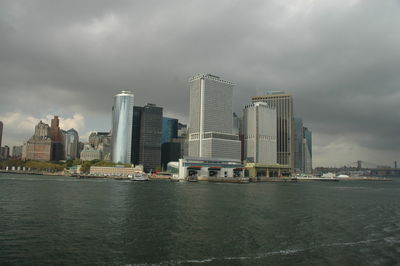 Sea by modern buildings against sky in city