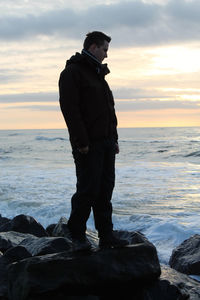 Full length of man standing on rock by sea