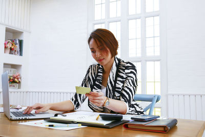 Businesswoman using credit card and laptop at desk in office