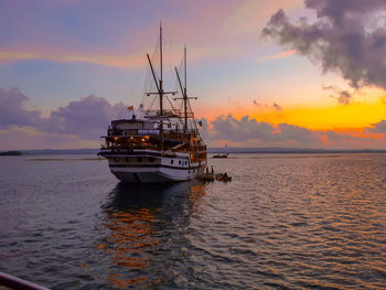 Sailboat sailing on sea against sky during sunset