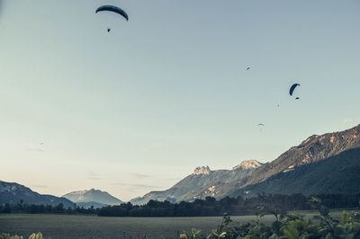 Birds flying over mountains against sky