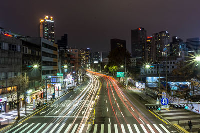 High angle view of light trails on street amidst buildings at night