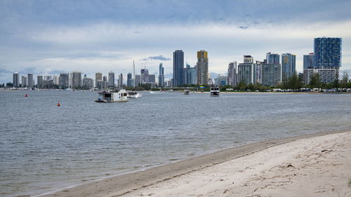 Sea by modern buildings against sky in city