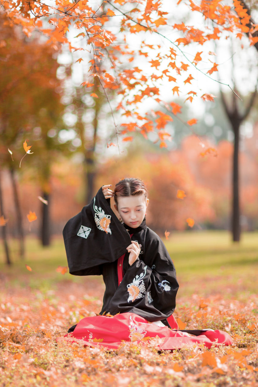 autumn, leaf, tree, change, one person, real people, orange color, maple leaf, nature, front view, full length, outdoors, leisure activity, day, young women, beauty in nature, lifestyles, halloween, young adult, people