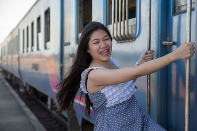 Happy woman hanging at entrance of train