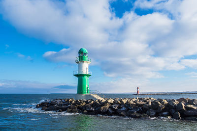 Lighthouse by sea against sky