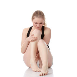 Young woman sitting against white background