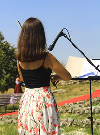 Rear view of woman with umbrella standing against sky