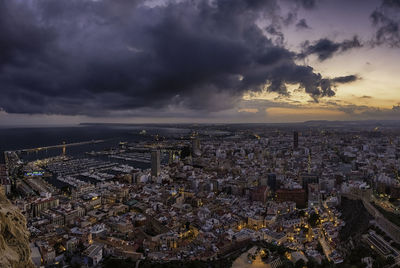 Aerial view of city against cloudy sky during sunset