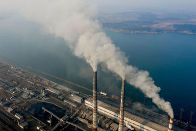 High angle view of smoke emitting from factory against sky