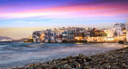 Buildings by sea against sky during sunset at mykonos