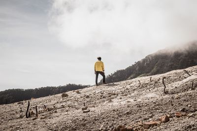 Rear view of man standing on mountain against sky