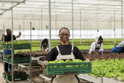 Portrait of young woman using mobile phone in greenhouse