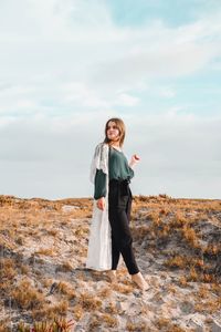 Fashionable woman standing on field against sky