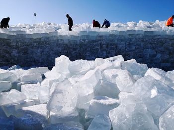 People on stack of ice against clear sky