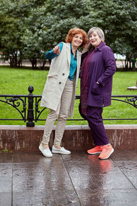 Full length portrait of a smiling young woman in rain