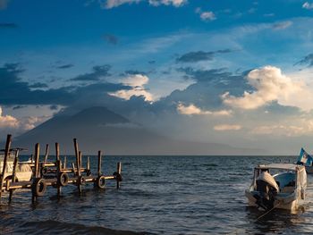 Fishing boats moored in sea against sky during sunset