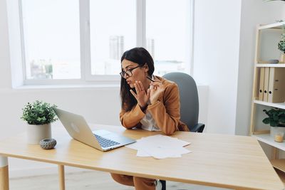 Young woman using laptop at desk in office