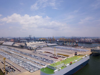 Aerial logistics commercial vehicles waiting to be load on to a car carrier ship at dockyard