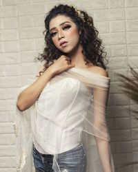 Portrait of beautiful young woman standing against wall