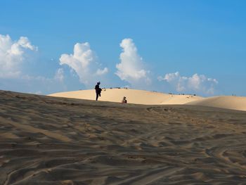 People walking on desert against sky