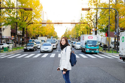 Portrait of woman standing on road in city