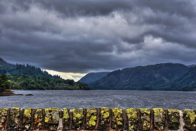 Scenic view of lake and mountains against storm clouds