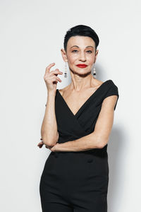 Portrait of young woman standing against white background