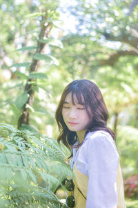 Young woman standing against plants