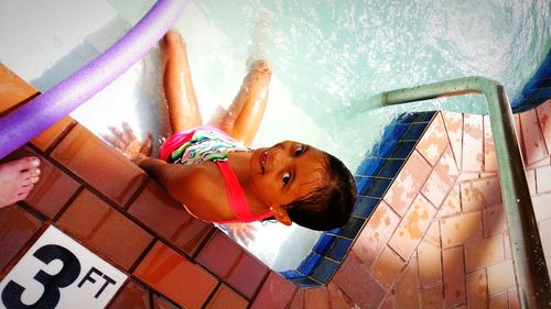 Low angle view of boy wearing multi colored umbrella