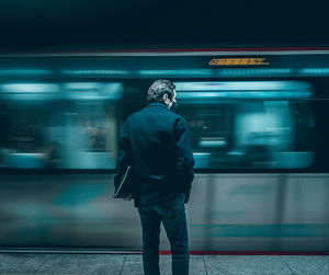 Rear view of man standing at railroad station platform