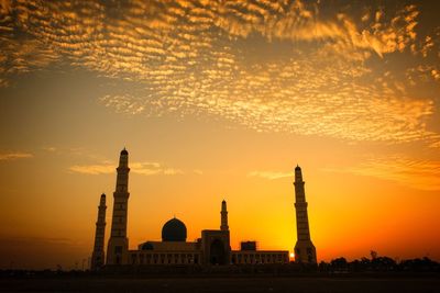 Low angle view of mosque against orange sky during sunset