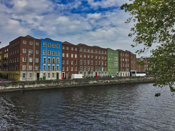 Buildings by river against sky in city