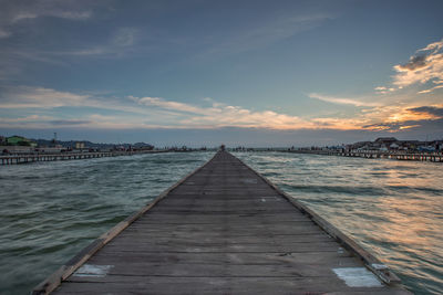 Pier over sea against sky during sunset