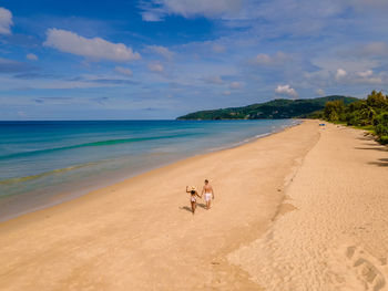 Scenic view of people on beach against sky