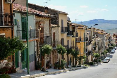 Houses in a slope distribution in a small village of sicily with trees near the street