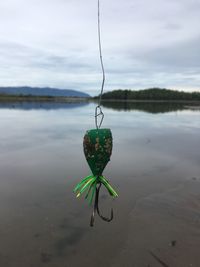 Close-up of fishing hanging over lake against sky