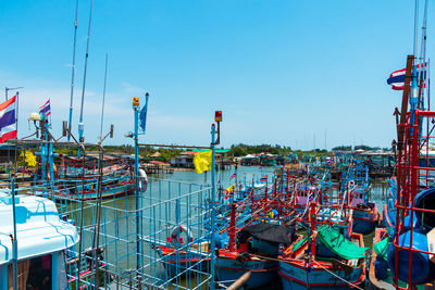 Fishing boats moored at harbor against clear sky