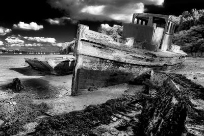 Abandoned boat moored on beach against sky