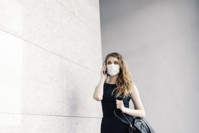 Full length of woman standing against wall