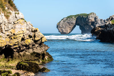 Scenic view of rocks in sea against clear blue sky