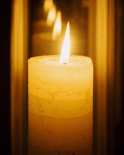 Close-up of lit candle in darkroom