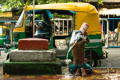 Rear view of boy bathing on footpath