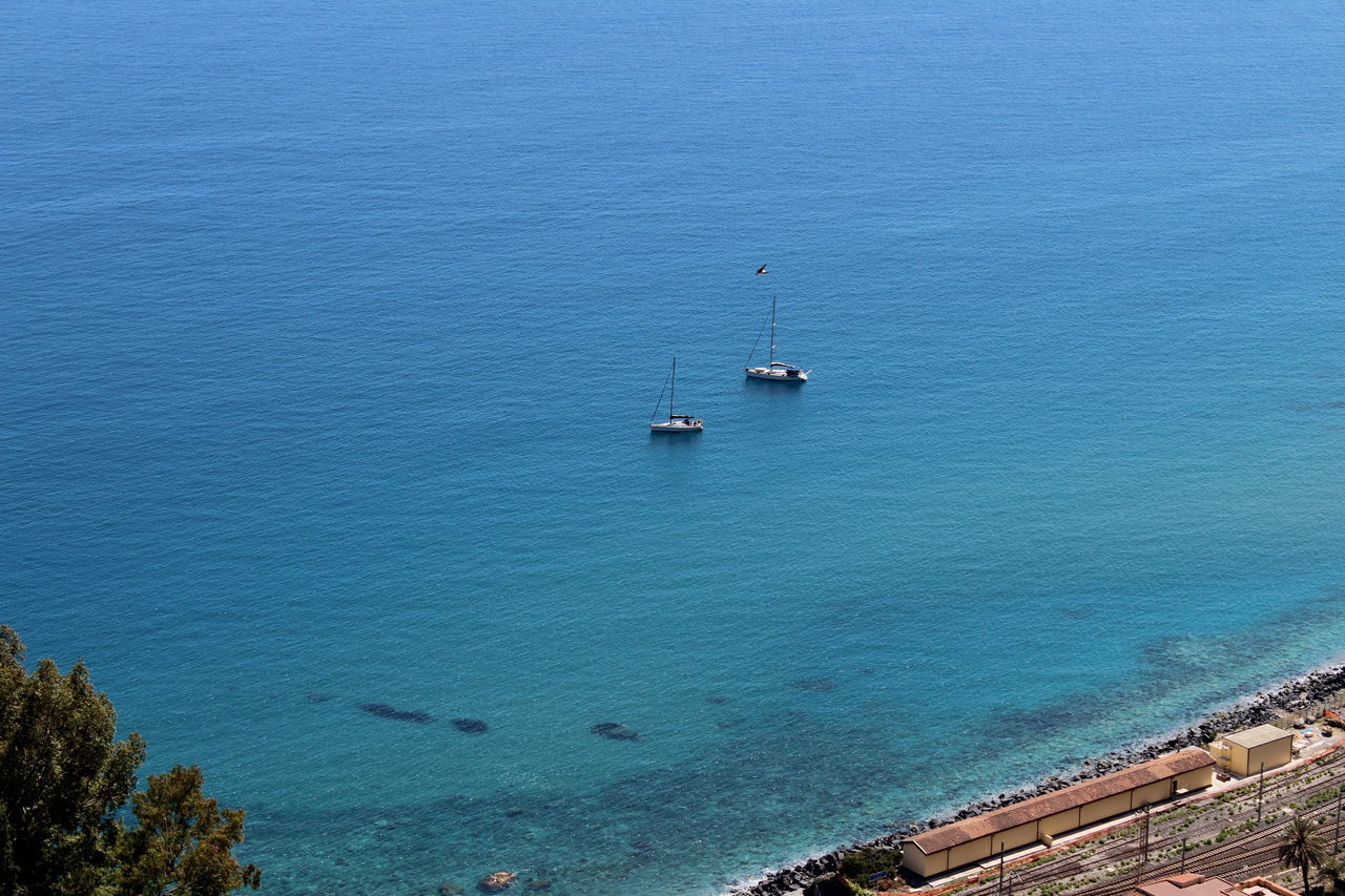 HIGH ANGLE VIEW OF BOATS MOORED ON SEA