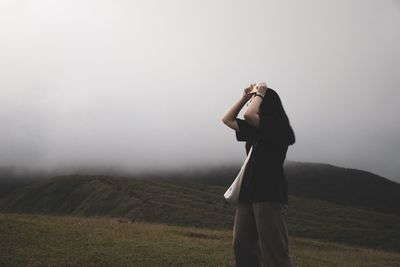 Woman standing on landscape during foggy weather