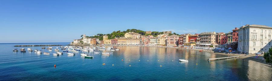 Panoramic view of sea and buildings against clear blue sky