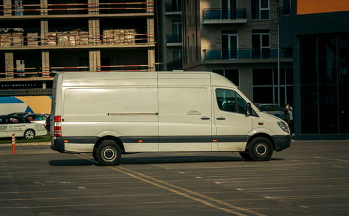 Side view of car parked on road against building