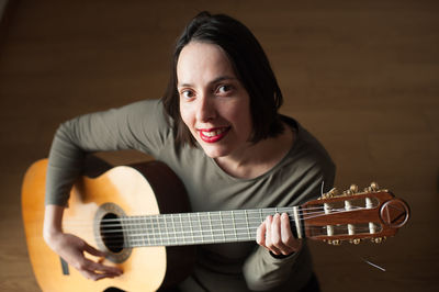 Portrait of woman playing guitar at home