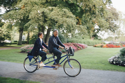 Full length of senior couple enjoying tandem bike ride in park